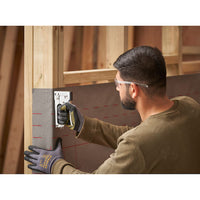 Wearing safety glasses and gloves, a man uses the STANLEY® Light-duty Steel Staple Gun to attach material to a wooden frame at a construction site.