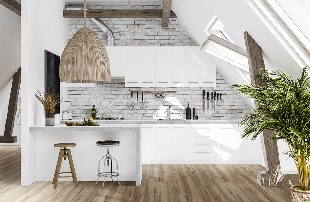 Modern attic kitchen with white cabinets, exposed beams, brick wall, woven pendant light, two bar stools at an island, and a potted plant by a slanted window—featuring Msisurfaces Akadia Luxury Vinyl Plank for stylish, waterproof durability.