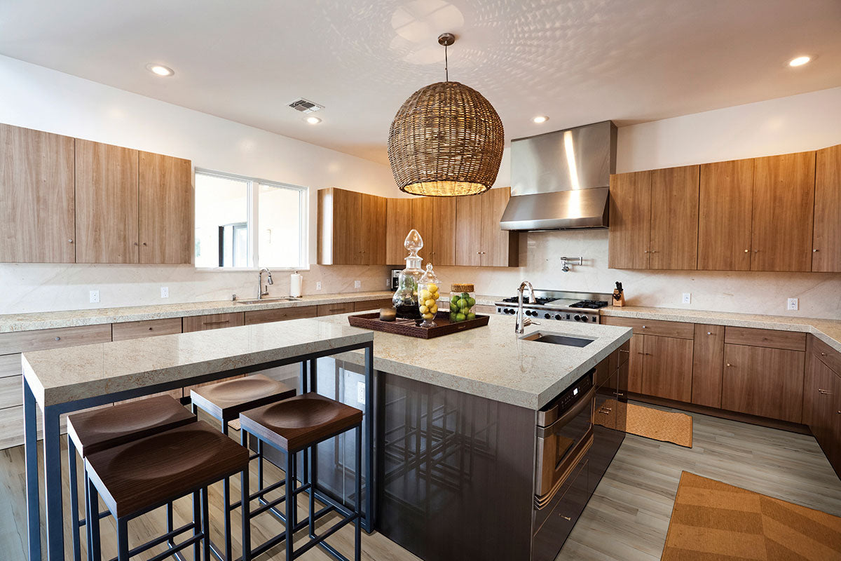 Modern kitchen featuring wooden cabinets, a large island with three stools, stainless steel appliances, a woven pendant light, decorative jars on the island, and Msisurfaces Akadia Luxury Vinyl Plank scratch-resistant flooring.
