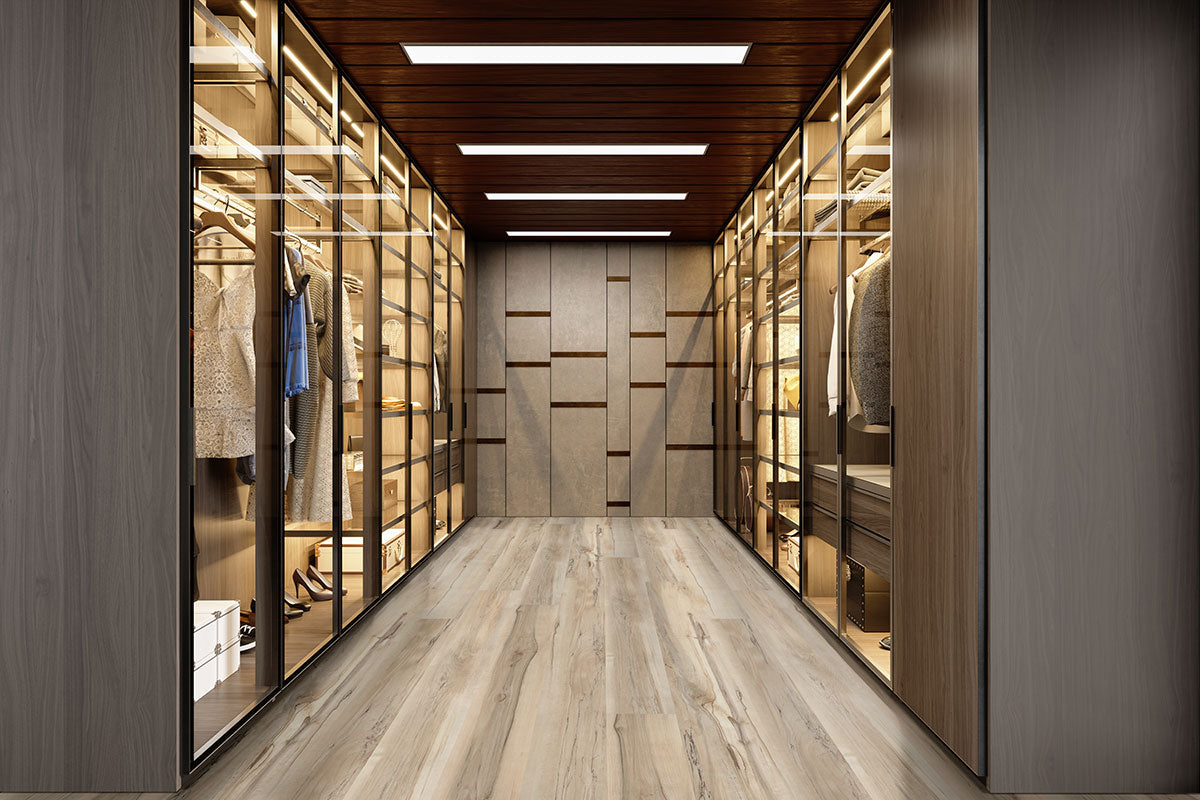 A modern walk-in closet features glass-fronted wooden cabinets, a patterned wood ceiling, recessed lighting, and Akadia Luxury Vinyl Plank waterproof flooring by Msisurfaces for a tidy, well-lit display of clothes and accessories.