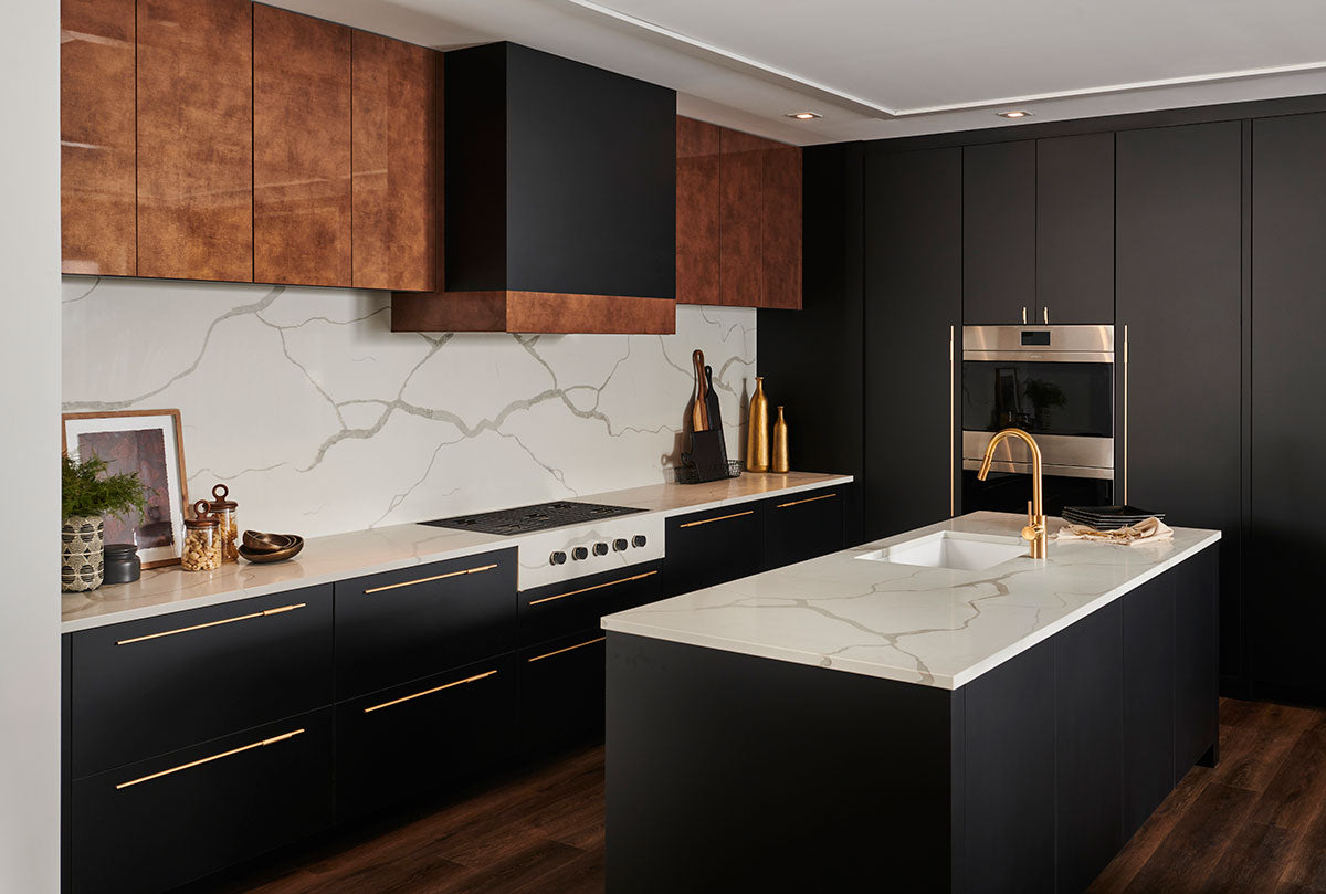 Modern kitchen with black and brown cabinets, marble counters, gold accents, an island with a gold faucet, built-in oven, and décor—all beautifully enhanced by durable MSI Cyrus Barrell Luxury Vinyl Planks (CrystaLux™ layer).