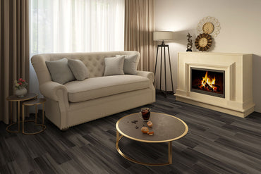 A cozy living room with a beige sofa, gray cushions, coffee table, fireplace, and lamp features MSIs Cyrus Jenta Luxury Vinyl Planks flooring (23.77 SQFT/box), offering waterproof SPC core durability and a stylish dark wood look.