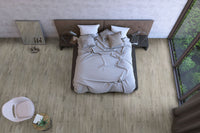 Top-down view of a modern bedroom with an unmade bed, bedside tables with lamps, MSI Cyrus Dunite Oak Luxury Vinyl Planks flooring, large window with greenery, a chair and small round table, and a floor mirror against the wall.