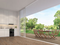 Modern kitchen with white cabinets and wooden floor features MSI Cyrus Fauna Luxury Vinyl Planks (23.77 SQFT/BOX), and opens to a spacious outdoor patio with dining set, overlooking a green lawn and trees under a clear sky.