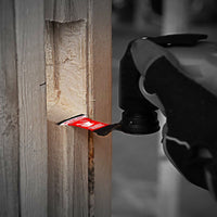 A close-up shows a gloved hand holding a power tool with Diablos DIABLO DOS125CGP3 1-1/4 in. AMPED™ Demo Demon™ Starlock Carbide Teeth Oscillating Blade cutting through wood. The red blade, featuring carbide teeth for durability, is in focus against a slightly blurred background.