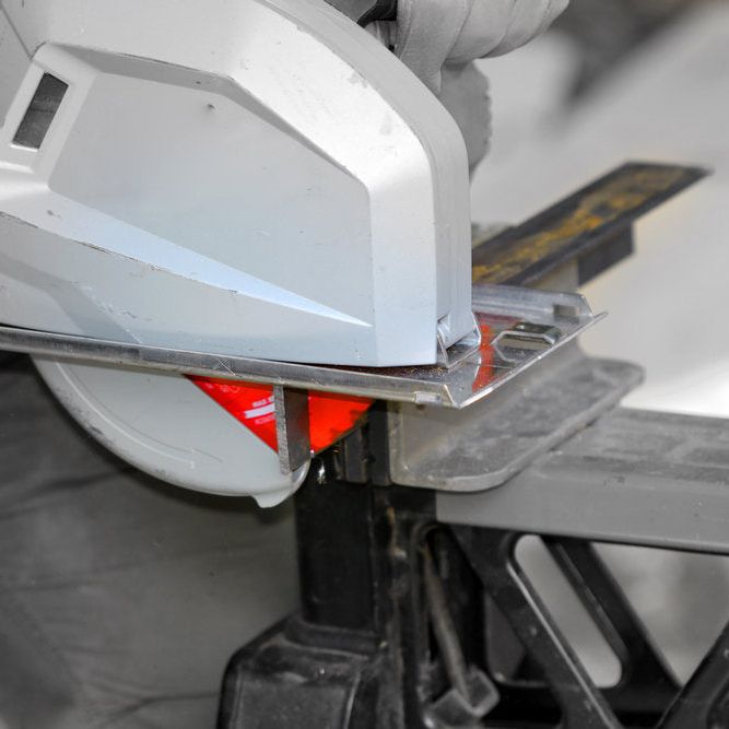 A person uses a circular saw with the Diablo DIABLO D0842CF 8 in. x 42-Teeth Steel Demon™ Cermet II Saw Blade on a black workbench to cut metal. The blade guard and protective gloves highlight the precision in cutting thick metal.
