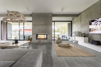 Modern living room featuring MSI Katella Luxury Vinyl Planks (23.77 sq ft/box) waterproof flooring, concrete walls, central fireplace, large windows, cozy sectional sofa, woven rug with cushions, wooden dining table, and wall-mounted TV.