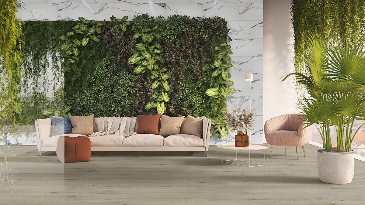 A modern living room features a beige sofa, pink armchair, white coffee table, and lush green vertical garden on marble; MSI Cyrus Runmill Isle Luxury Vinyl Planks provide durable waterproof flooring that enhances the bright, serene space with large plants.