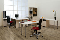 Modern office with three desks, black mesh chairs with red cushions, computers, organizers, potted flowers, and shelves by a bright window wall. Light wood furniture complements MSI Cyrus Walnut Waves Luxury Vinyl Planks flooring.