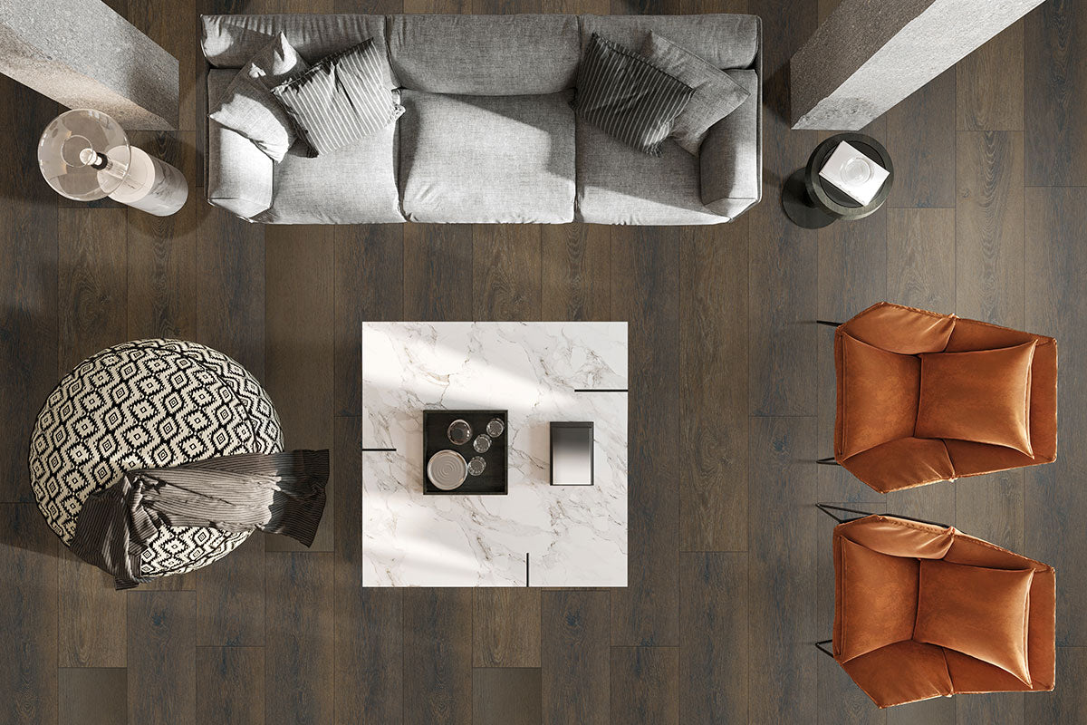 Overhead view of a modern living room with gray sofa, brown armchairs, patterned ottoman, and white marble coffee table atop MSI XL Cyrus Barrell Luxury Vinyl Planks, adding waterproof style with dark wood rigid-core flooring.