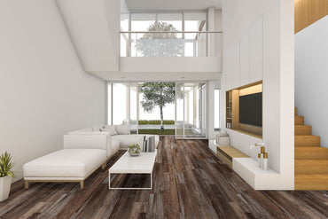 Modern living room with white walls, high ceiling, large windows, a white sectional sofa, coffee table, built-in shelving, stairs, and waterproof MSI XL Cyrus Bembridge Luxury Vinyl Planks flooring. Tree visible outside through glass doors.