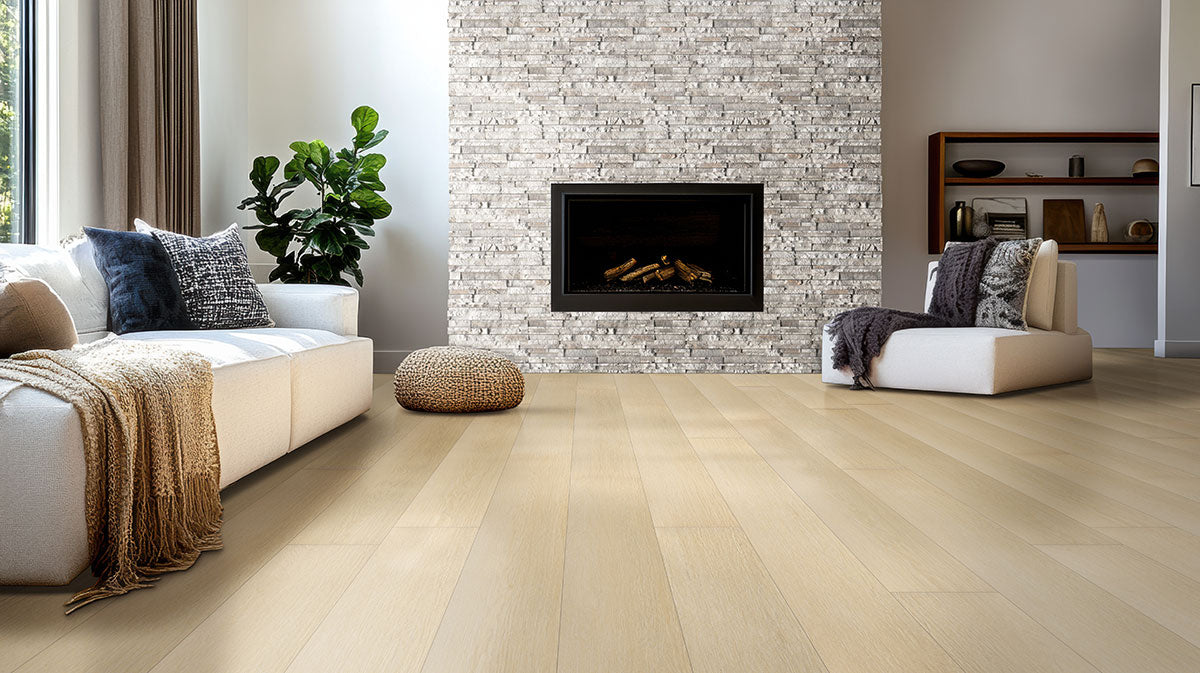 Modern living room with MSI XL Cyrus Lenexa Creek Luxury Vinyl Planks (22.44 sqft box), CrystaLux™ wear layer, stone fireplace, white and beige furniture, woven pouf, potted plant, and shelves on a white-gray wall.