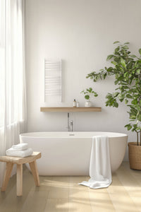 A modern bathroom with a white freestanding tub, wooden stool and towels, a large potted plant, MSI XL Cyrus Lenexa Creek Luxury Vinyl Planks flooring (22.44 SQFT/box), towel rail, and natural light through sheer curtains.