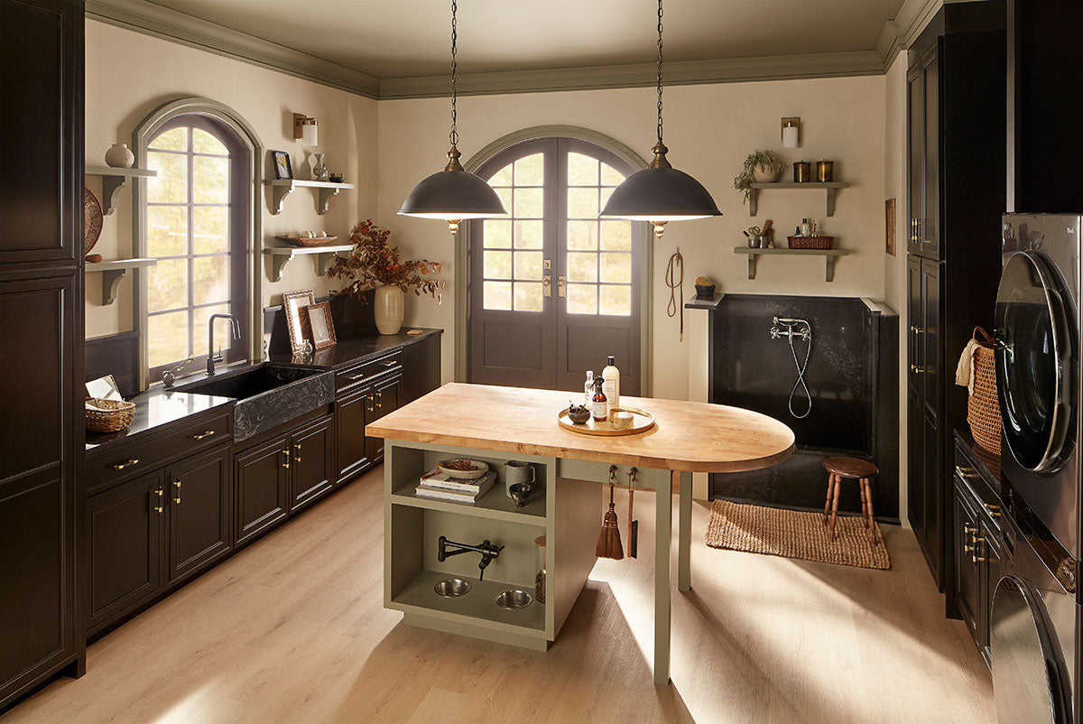 A stylish laundry room with dark cabinets, a farmhouse sink, pendant lights, wood island, wall shelves with decor, washer and dryer, MSI XL Cyrus Runmill Isle Luxury Vinyl Planks flooring with CrystaLux Protection, and a pet washing station.