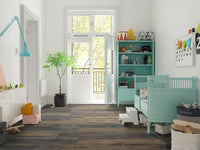 Bright, modern nursery with teal furniture, crib, shelving, potted plant, wall art, and toys. Large windows fill the room with light. MSI’s XL Cyrus Stable Luxury Vinyl Planks add stylish warmth and durability to the space.