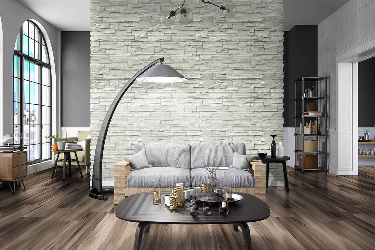 Modern living room with a gray stone accent wall, gray sofa, arched window, wooden floor featuring MSI XL Cyrus Jenta Luxury Vinyl Planks, tall arc lamp, dark coffee table, plus shelves and extra seating.