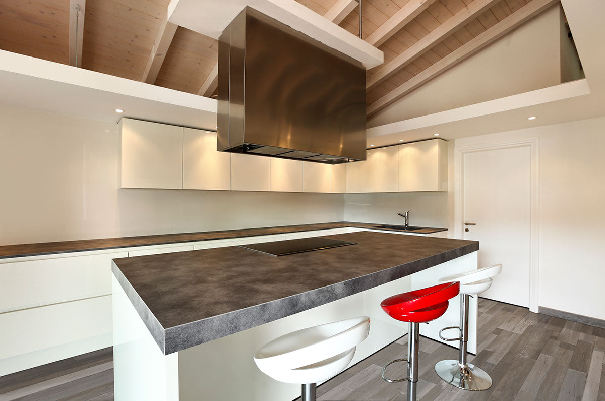 Modern kitchen with a large island, three bar stools (two white, one red), sleek white cabinets, built-in stovetop, and stainless steel range hood. The wood ceiling with exposed beams matches urban gray MSI XL Cyrus Woburn Abbey LVP flooring.