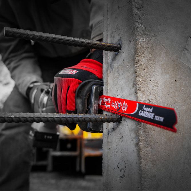 An expert uses a Diablo DS0608CFA3 6 in. 8TPI AMPED™ Steel Demon™ carbide reciprocating saw blade, effortlessly cutting metal rebar from concrete. The grayscale backdrop highlights the vivid red tool in this dynamic scene.